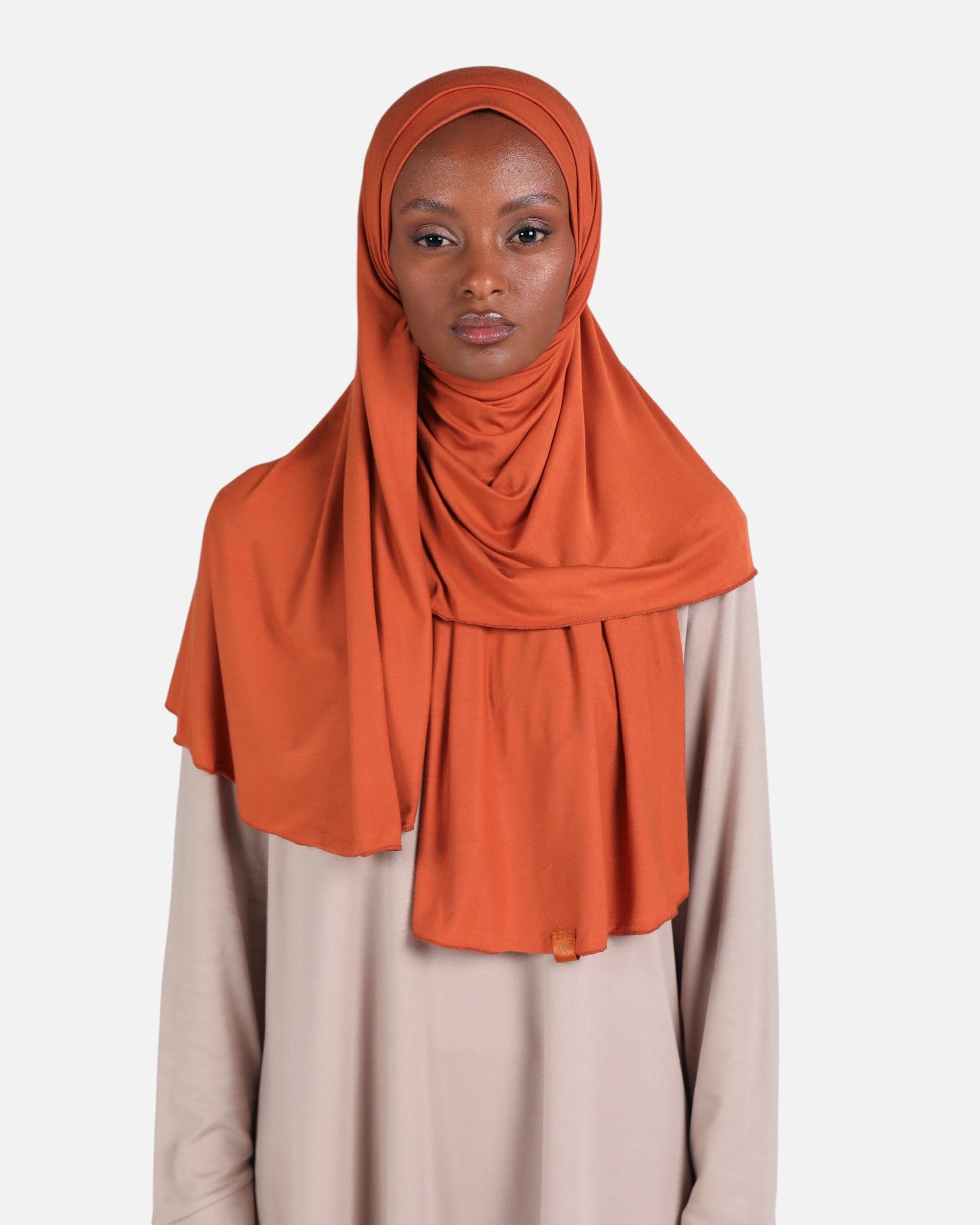 Woman wearing an orange hijab against a white background